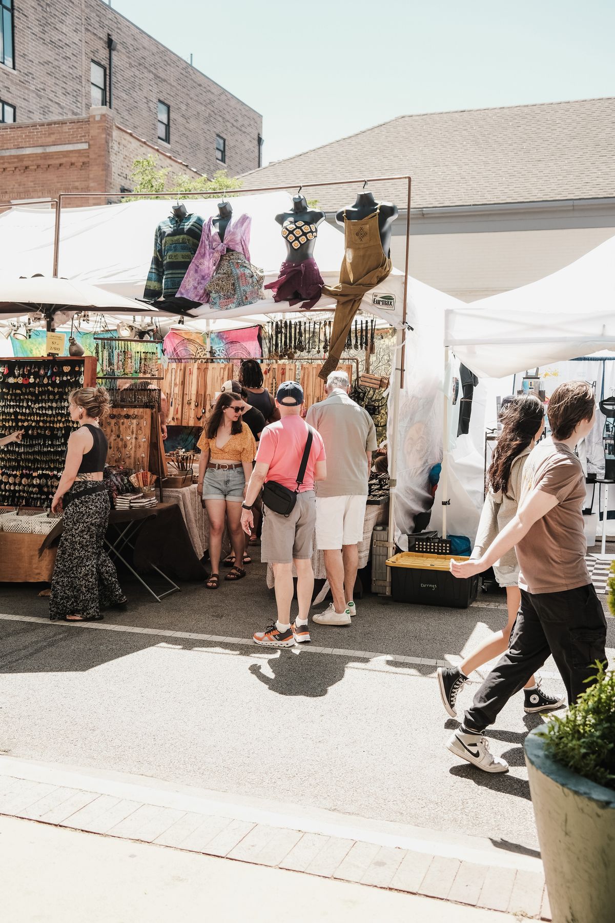 People in casual clothing walking between stalls at an outdoor market